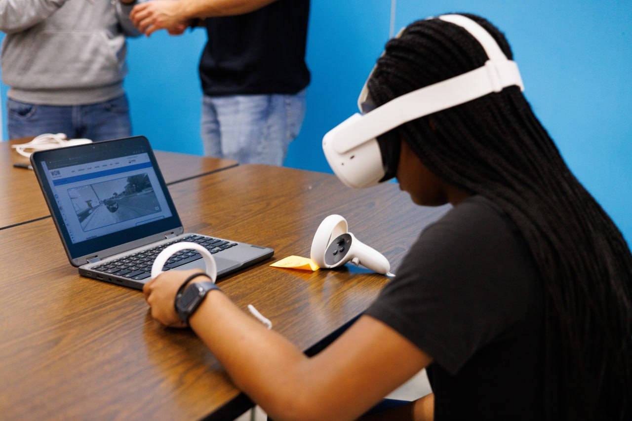 A young person exploring a digital experience with a virtual reality headset and laptop